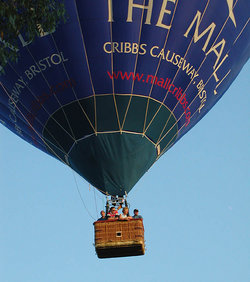 A hot air balloon over Bristol, England, showing the wickerwork passenger basket. This balloon carries advertising for a shopping centre.