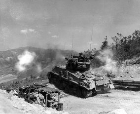 A US Sherman tank fires from a prepared position during the Korean war.