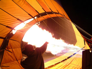 A hot air balloon is inflated by a bank of propane torches, just before dawn.
