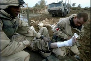 US soldiers putting bandages on a wounded in Iraq.