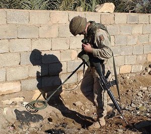A U.S. Army soldier uses a metal detector to search for weapons and ammunition in Iraq