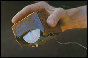 The first computer mouse held by inventor Douglas Engelbart showing the wheels which directly contact the working surface.