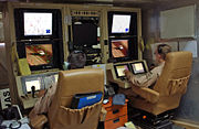 A pilot and sensor operator man the controls of a MQ-1 Predator Unmanned Aerial Vehicle from the control room at Balad Air Base, Iraq